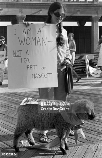 On the Atlantic City Boardwalk, a demonstrator carries a poster that reads 'I Am A Woman, Not a Toy, Pet, or Mascot' and holds a live sheep on a...