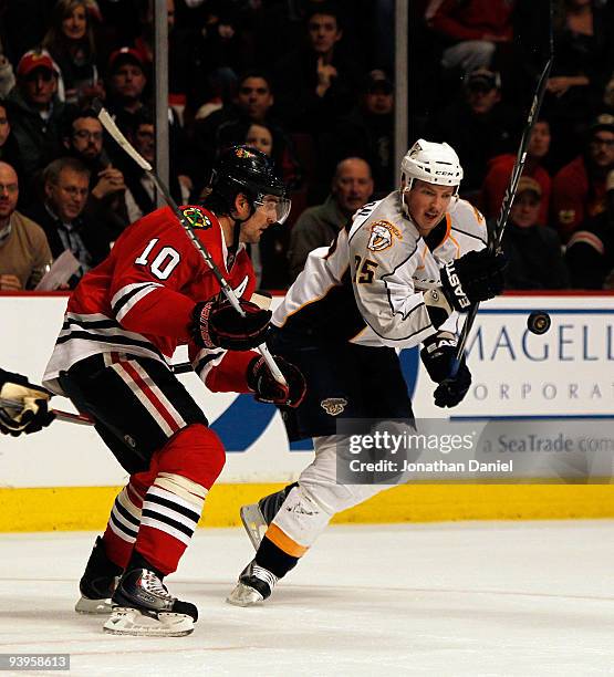 Patrick Sharp of the Chicago Blackhawks and Jerred Smithson of the Nashville Predators keep their eyes on a flying puck at the United Center on...