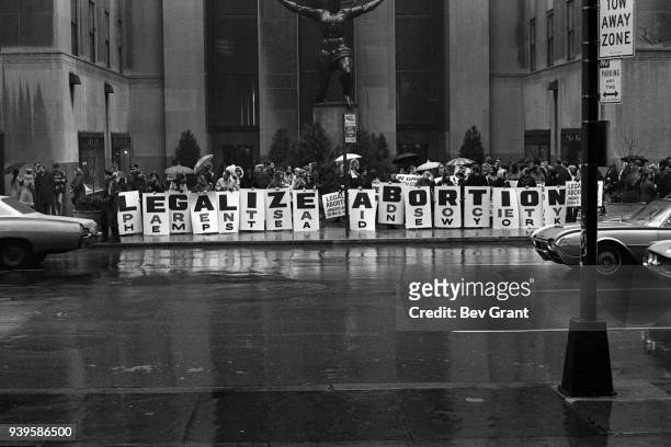 In front of the Atlas sculpture at Rockefeller Center, activists hold a series of signs that read 'Legalize Abortion' during a demonstration, New...