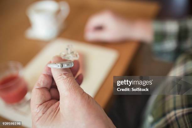 senior man holding his hearing aid - hearing aids stock pictures, royalty-free photos & images