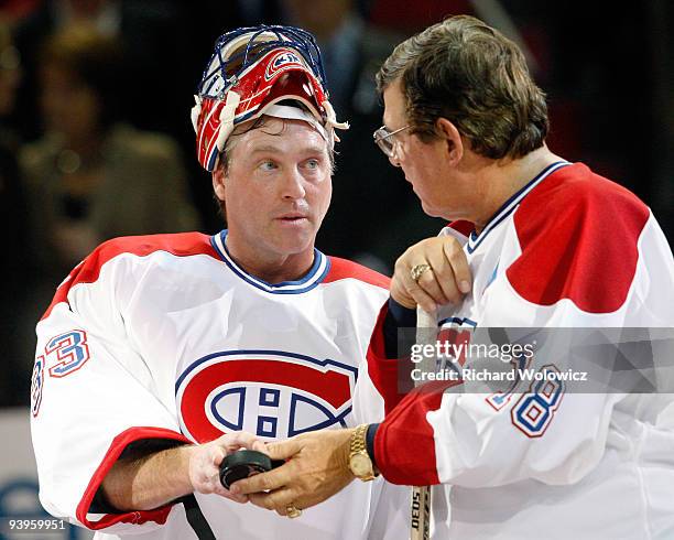 Former Montreal Canadiens Serge Savard hands a puck to Patrick Roy during the Centennial Celebration ceremonies prior to the NHL game between the...