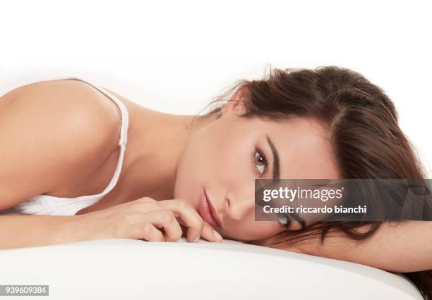 brunette woman with natural look laying in bed - brunette woman bedroom stock-fotos und bilder