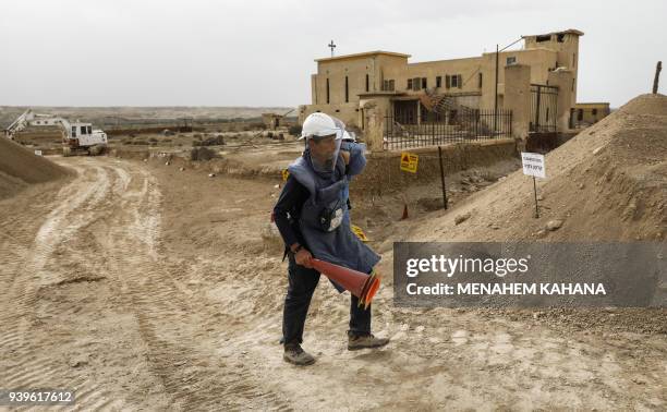 An employee of the HALO Trust, a UK-based non-profit demining organization, walks carrying safety funnels on-site at Qasr al-Yahud in the occupied...