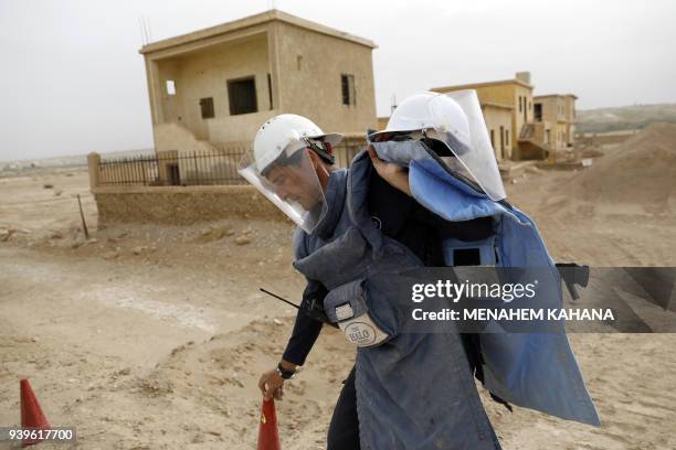 An employee of the HALO Trust, a UK-based non-profit demining organization, walks carrying a safety funnel on-site at Qasr al-Yahud in the occupied...