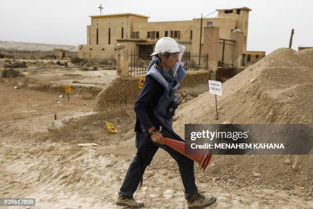 An employee of the HALO Trust, a UK-based non-profit demining organization, walks carrying safety funnels on-site at Qasr al-Yahud in the occupied...