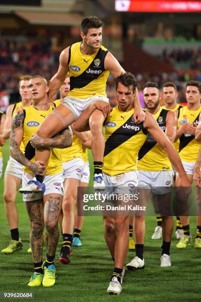 Trent Cotchin of the Tigers is chaired off the field by Dustin Martin of the Tigers and Alex Rance of the Tigers during the round two AFL match...