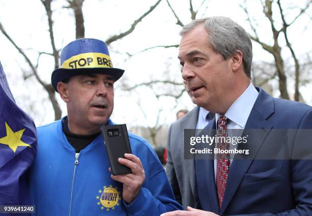 Nigel Farage, former leader of the U.K. Independence Party , right, is filmed by an anti-Brexit demonstrator as he departs Millbank in London, U.K.,...