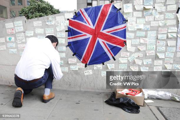 Man places a message on the wall in honor of the victims of the terrorist attack at in London on June 9, 2017.