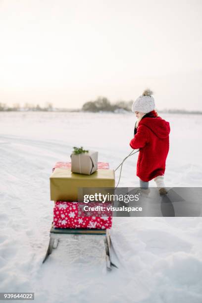 niedliche kleine mädchen mit weihnachten präsentiert auf einem schlitten - skandinavische kultur stock-fotos und bilder