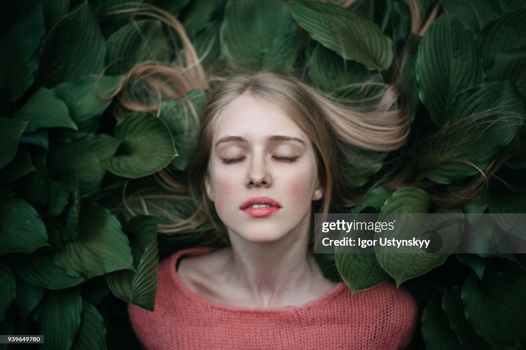 Portrait of woman laying on the green leaves