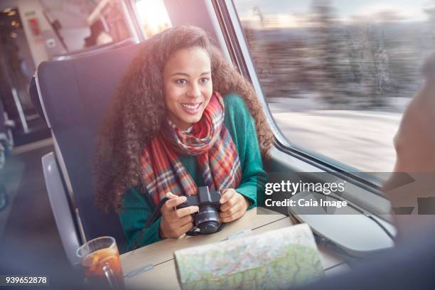 smiling young woman with camera and map riding passenger train - train interior stock pictures, royalty-free photos & images