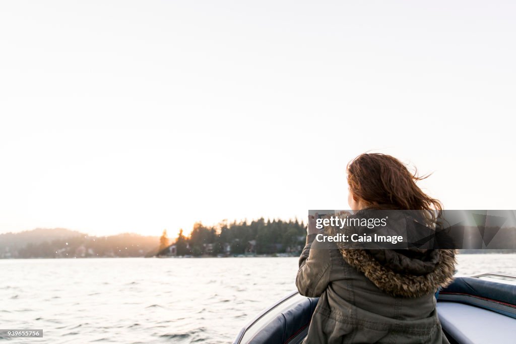 Woman using camera phone, photographing tranquil lake