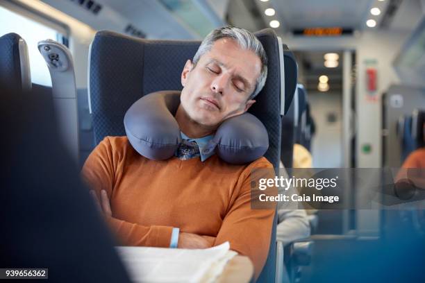 tired businessman with neck pillow sleeping on passenger train - neck pillow stock pictures, royalty-free photos & images
