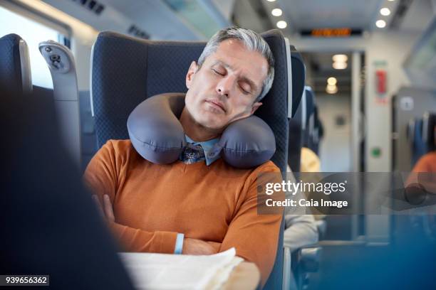 tired businessman with neck pillow sleeping on passenger train - tåginteriör bildbanksfoton och bilder