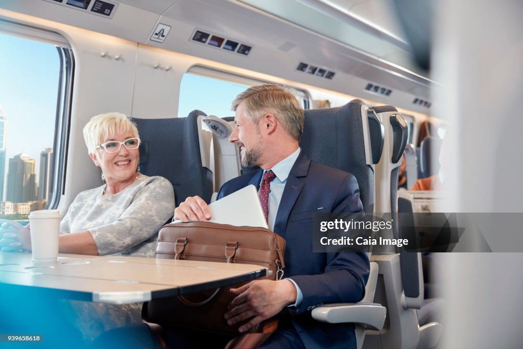 Businessman and businesswoman working, talking on passenger train