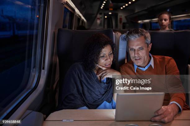 couple using digital tablet on dark passenger train at night - treno passeggeri foto e immagini stock