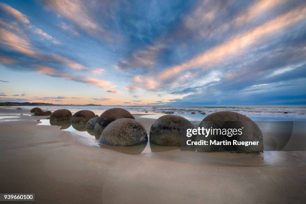 moeraki boulders on koekohe beach with dramatic sky, otago coast, south island of new zealand. moeraki, hampden, koekohe beach, otago coast, south island, new zealand. - otago landscape stock pictures, royalty-free photos & images