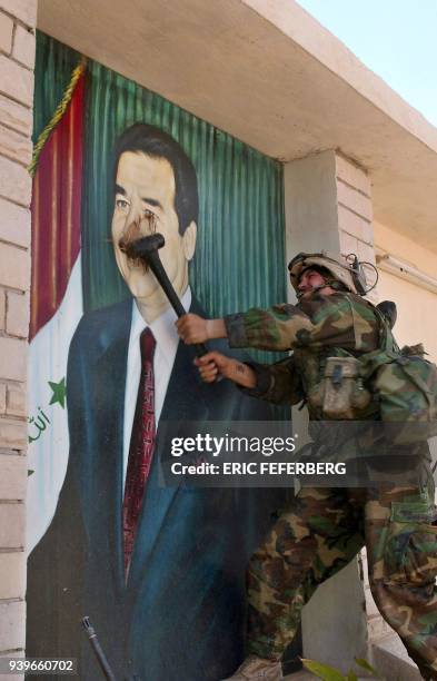 Marine from the 2nd Battalion/8th Regiment destroys a portrait of Iraqi President Saddam Hussein at the entrance of the aluminium complex factory in...