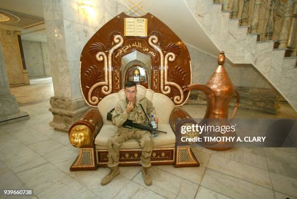 Soldier sits in a seat at the Radwaniyah Palace used during the toppled regime of Iraqi leader Saddam Hussein as a reception palace for guests near...