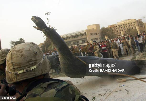 Statue of Saddam Hussein falls as it is pulled down by a US armored vehicle in Baghdad's al-Fardous square 09 April 2003. US troops moved into the...