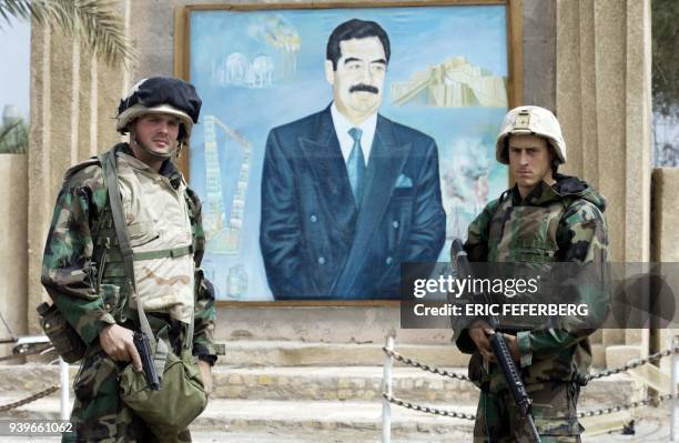 Marines pose for a souvenir picture in front of a portrait of Iraqi President Saddam Hussein 24 March 2003 in Nasiriyah. A US marine officer said the...