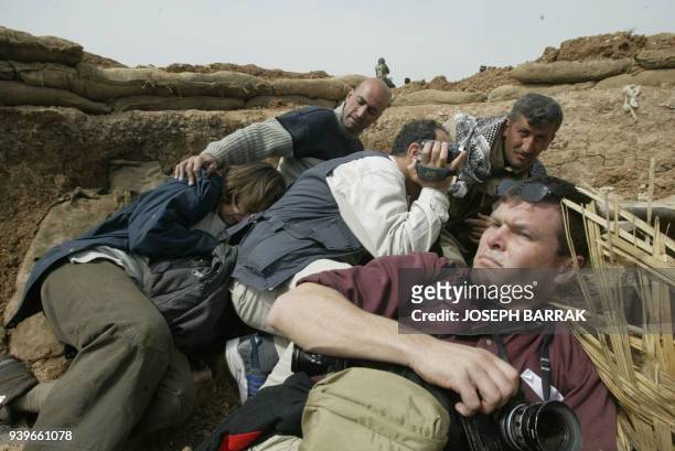 Journalist take cover as Kurdish peshmerga volunteer fighters of the Kurdistan Democratic Party fire on an Iraqi army post close to the village of...