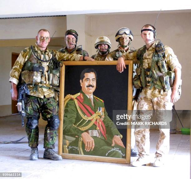 Members of the Desert Rats - Zulu Company, British Royal Fusiliers, pose with a portrait of Iraqi leader Saddam Hussein taken from the local Ba'ath...