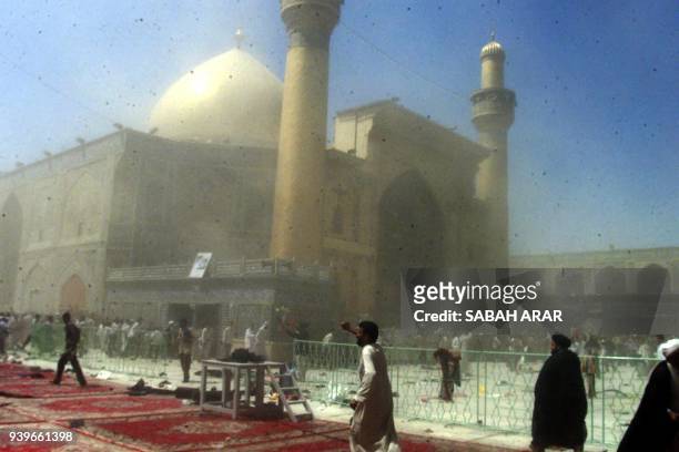 Iraqi men flee following an explosion 29 August 2003, inside the Shrine of Imam Ali, one of Shiite Islam's holiest shrines in the central city of...