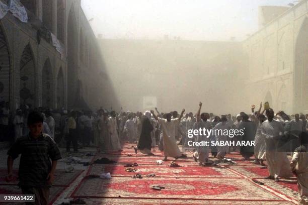 Iraqi men flee following an explosion 29 August 2003, inside the Shrine of Imam Ali, one of Shiite Islam's holiest shrines in the central city of...