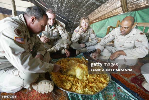 Soldiers dig into a dish of rice and chicken at the house of Sheikh Ali al-Ghazzi, head of the al-Ghazzi tribe, in Nasiriyah 30 November 2003. Sheikh...