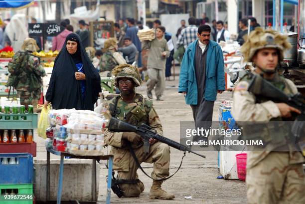 An Iraqi woman looks at products in the market as US soldiers of 1-22 Battalion of the 4th Infantry Division patrol the area in downtown of Tikrit,...