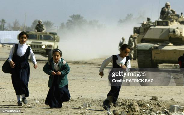 Iraqi schoolgirls flee an approaching US army patrol in the Baghdad suburb of Abu Gharib 05 November 2003. US-led troops and civilians seen as...