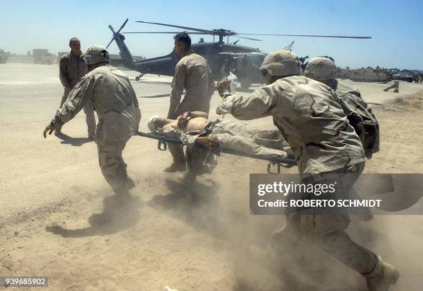 Military doctors and other soldiers carry a wounded soldier to a UH-60 medivac helicopter at a military base, some 60kms northeast of Baghdad 06 May...