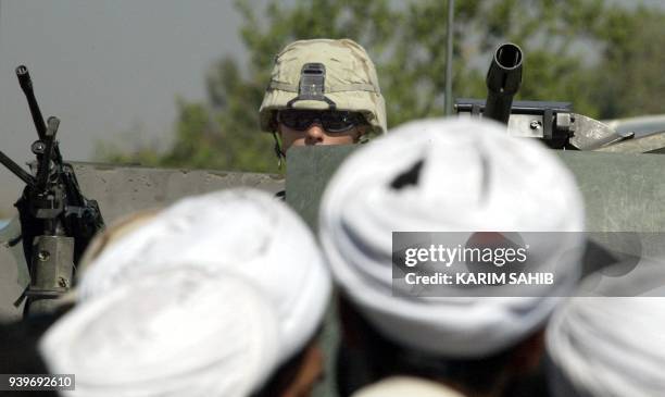 Iraqi Shiite Muslim clerics face a US soldier sitting on his armoured Humvee during a protest in Baghdad 08 October 2003 against the arrest of two...