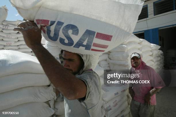 Iraqi workers haul sacks of flour donated by the United States in an open black market in the Sadr City locality of Baghdad 11 September 2003. The...