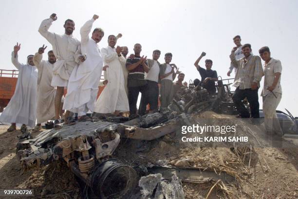 Iraqi residents chant "Allah Akbar", pro-Saddam and anti-US slogans in celebration atop a destroyed US military vehicle 12 September 2003 in the...