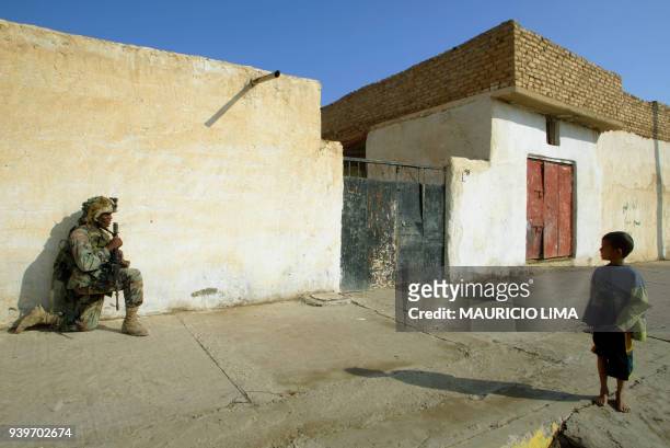 An Iraqi child looks at a US Army soldier from Charlie Company, part of 1-22 Battalion of the 4th Infantry Division , taking cover during a patrol in...