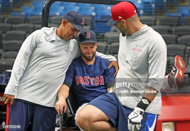 Boston Red Sox second baseman Dustin Pedroia sits in a cart with his leg up. His manager and close friend Alex Cora gave him a hug at one point. J.D....