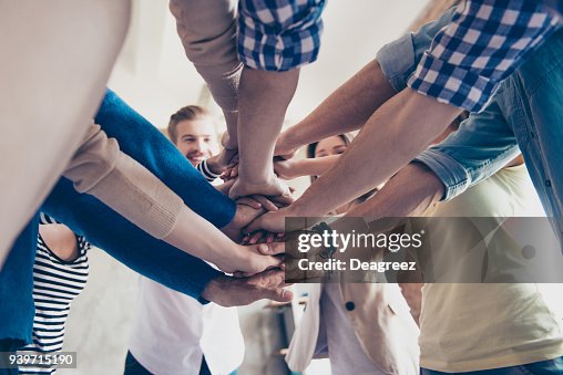 Låg vinkel beskuren bild av kollegor att sätta händerna ovanpå varandra, casual kläder. Begreppet lyckad teambuilding och enighet Låg vinkel beskuren bild av kollegor att sätta händerna ovanpå varandra, casual kläder. Begreppet lyckad teambuilding och enighet