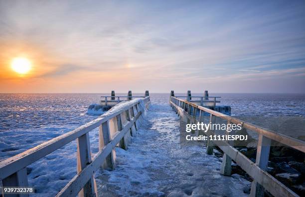 frozen lake with an icy jetty during sunrise - 1111iespdj stock pictures, royalty-free photos & images