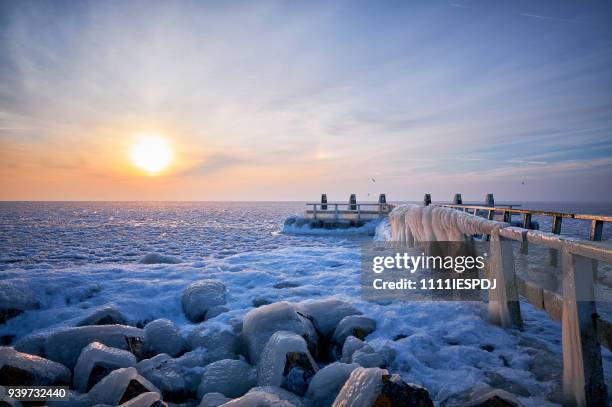 zugefrorenen see mit einem eisigen steg bei sonnenaufgang - 1111iespdj stock-fotos und bilder