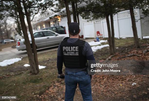 Customs and Border Protection officer watches a house as Homeland Security Investigations ICE agents detain a suspected MS-13 gang member and...