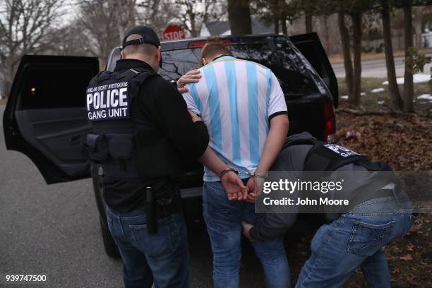 Homeland Security Investigations ICE agents frisk a suspected MS-13 gang member and Honduran immigrant after arresting him at his home on March 29,...