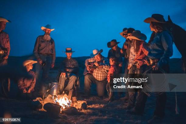 cowboys sitting around campfire - campfire storytelling stock pictures, royalty-free photos & images