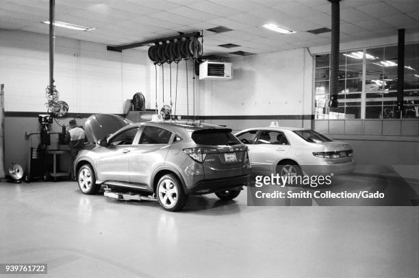 Interior of a motor vehicle repair center, with Honda automobile preparing to be lifted on a jack, Walnut Creek, California, February, 2018.
