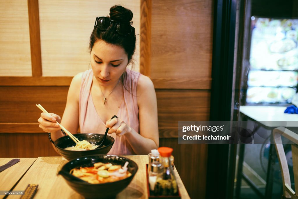 Young woman eating ramen noodles in a Japanese food place in Bangkok, Thailand