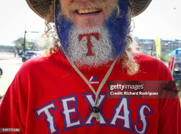 Texas Rangers fan makes his way to the ballpark with his beard decorated with the team's logo before the Opening Day game against the Houston Astros...