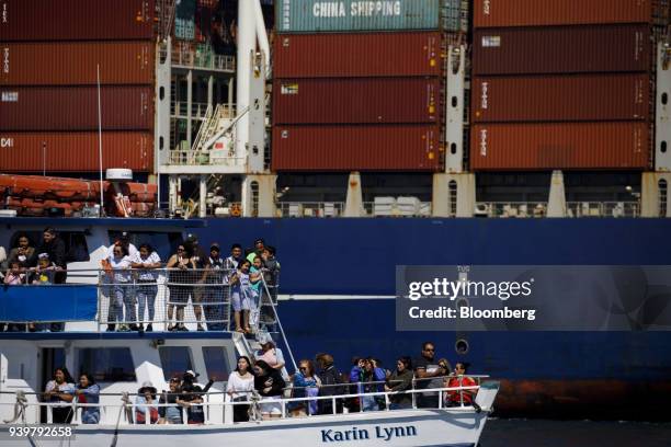 Tour boat passes a container ship at the Port of Los Angeles in Los Angeles, California, U.S., on Wednesday, March 28, 2018....