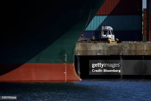 Truck drives past a container ship at the Port of Los Angeles in Los Angeles, California, U.S., on Wednesday, March 28, 2018....