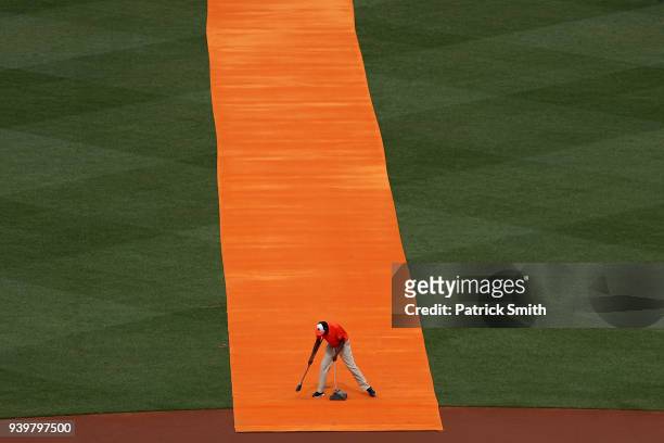 Member of the Baltimore Orioles grounds crew cleans an orange carpet before the Baltimore Orioles are introduced before they play against the...